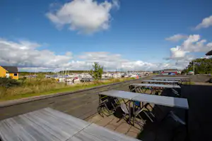 Terrasse mit Tischen und Stühlen, Blick auf einen Yachthafen mit vielen Segelbooten und Bootsstegen.