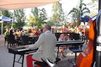 Strandcamping Seekirchen - Gäste bei einer Musikshow auf der Terrasse des Restaurants auf dem Campingplatz