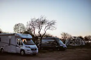 Sunny Nights Camping - Wohnmobile auf dem Parkplatz mit Iglogestell im Hintergrund