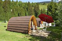 TCS-Camping Disentis - Mobilheim mit kleiner Terrasse Grill und Sonnenschirm auf dem Campingplatz