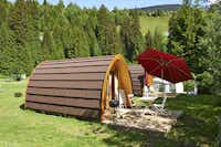 TCS-Camping Disentis - Mobilheim mit kleiner Terrasse Grill und Sonnenschirm auf dem Campingplatz