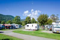 TCS-Camping Lugano - Stellplatz für Wohnwagen auf dem Rasen mit Blick auf Hügel auf dem Campingplatz