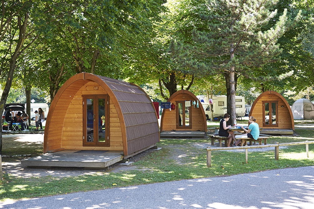 TCS-Camping Sion  - Gäste sitzen vor dem Mobilheim im Schatten der Bäume auf dem Campingplatz