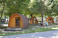 TCS-Camping Sion  - Gäste sitzen vor dem Mobilheim im Schatten der Bäume auf dem Campingplatz