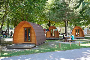 TCS-Camping Sion - Gäste sitzen vor dem Mobilheim im Schatten der Bäume auf dem Campingplatz