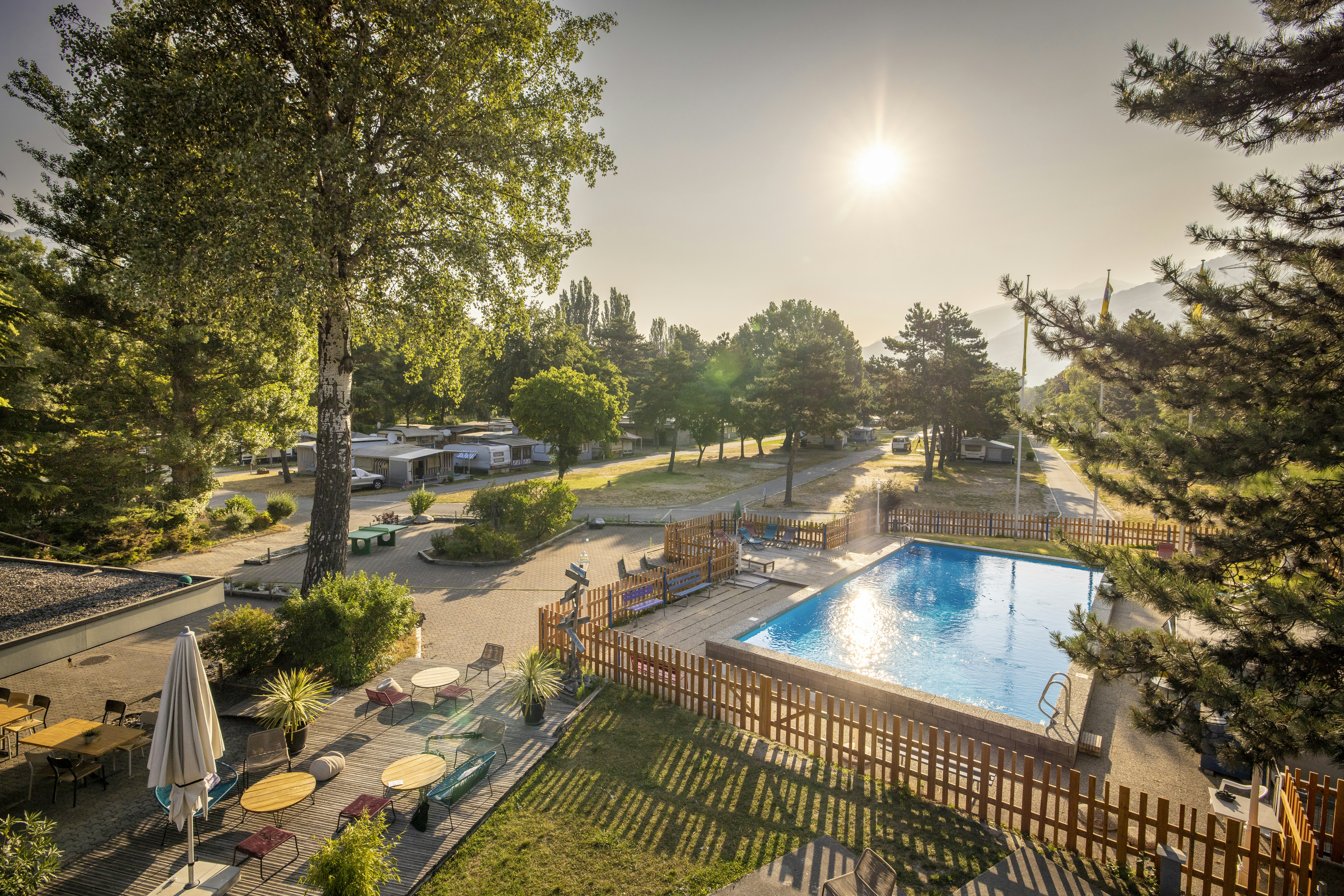 TCS Camping Sion - Blick auf den Campingplatz mit Pool im Freien und Terrasse