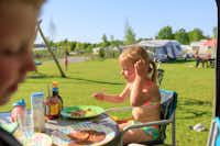 Vakantiepark Ackersate - Familien essen vor dem Wohnmobil im Schatten der Markise