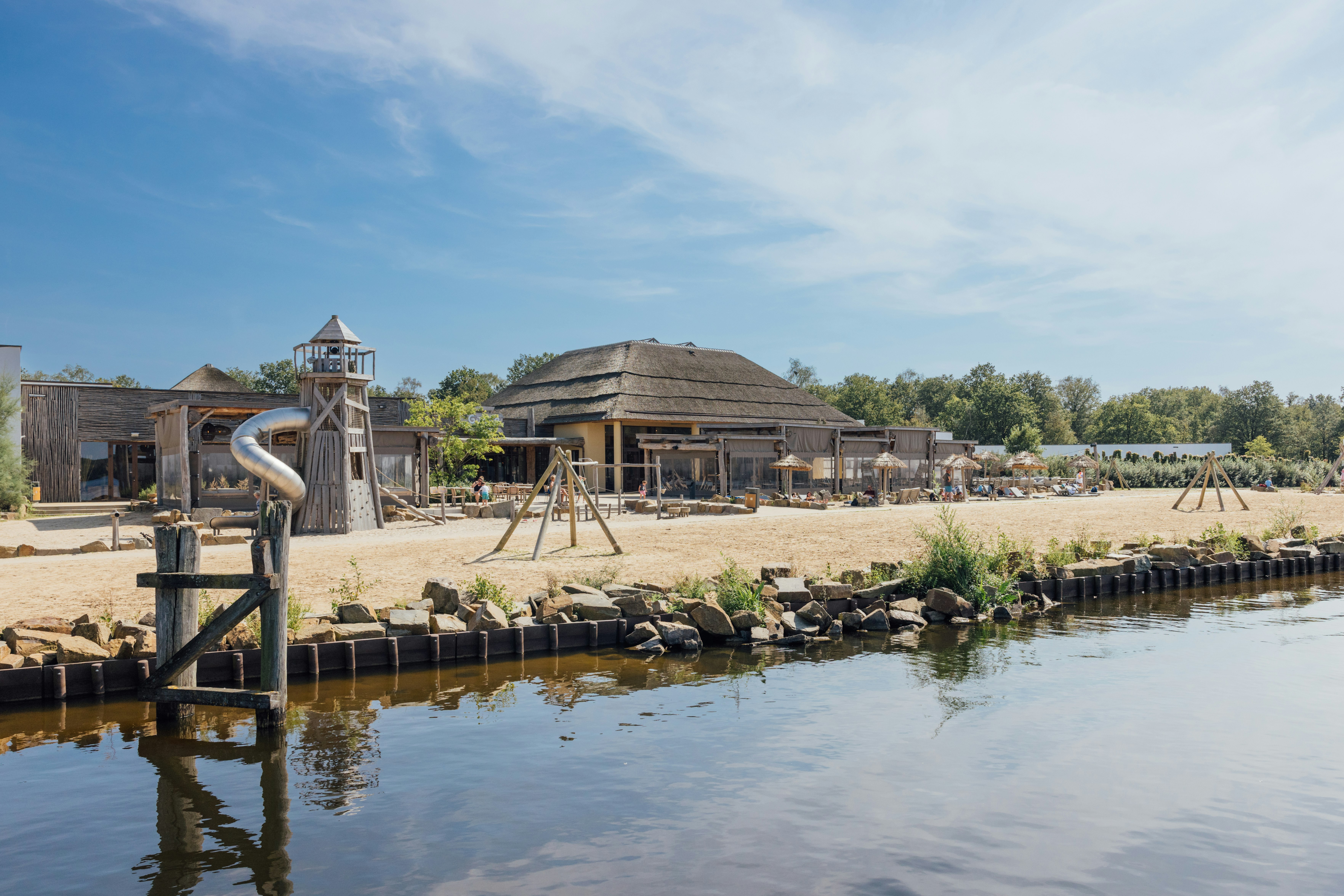 Vakantiepark Beekse Bergen - Blick vom Wasser auf das Festland mit Spielplatz am Strand