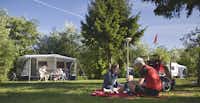 Vakantiepark De Luttenberg - vor dem Wohnmobil sitzen Camper im Schatten--