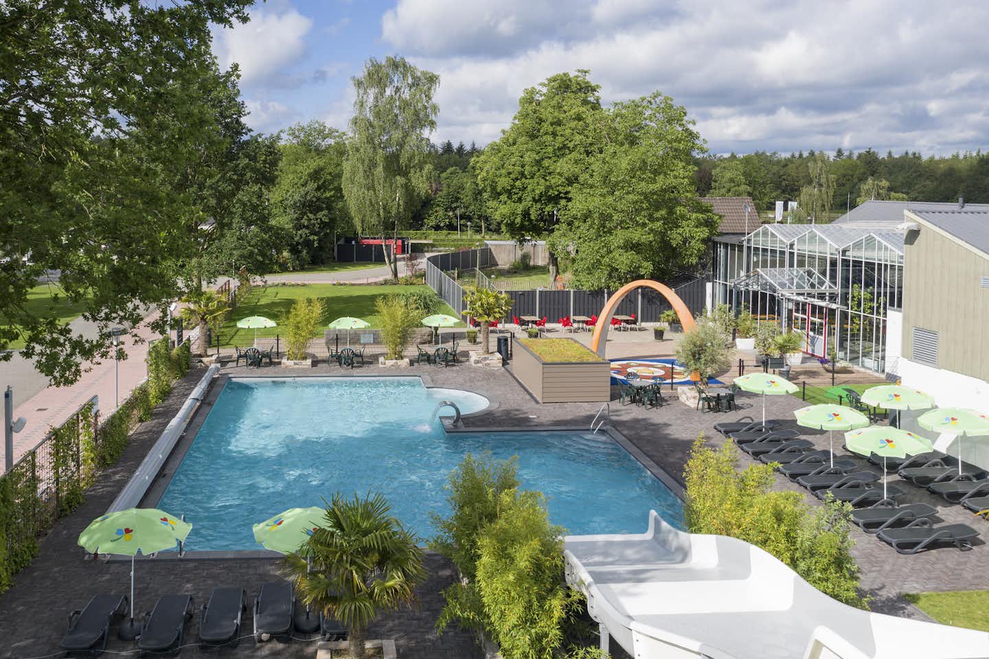 Vakantiepark 't Rheezerwold - Blick auf den Pool mit Wasserrutsche und Liegestühlen aus der Vogelperspektive