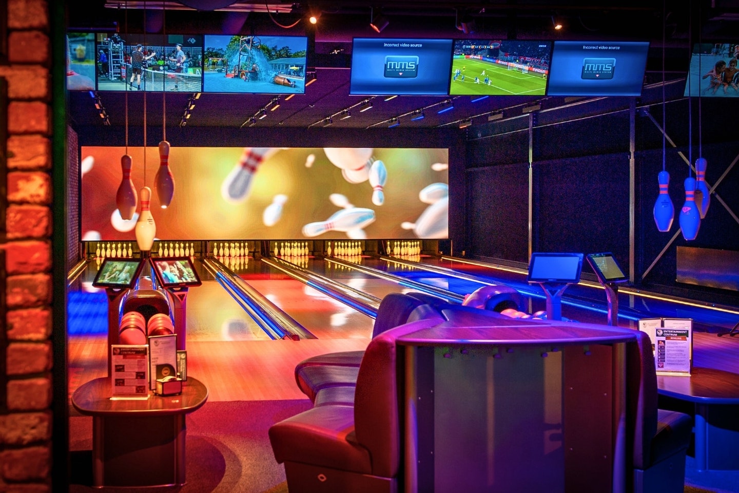Bowlingbahn im Campingcenter mit Kegelbahn, Kugeln, Bildschirmen und Beleuchtung an der Wand.