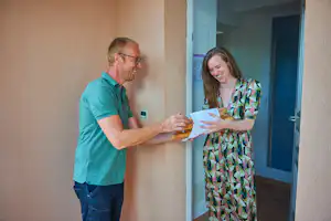 Ein Mann und eine Frau stehen am Eingang und übergeben sich Unterlagen an einer Camping-Rezeption.