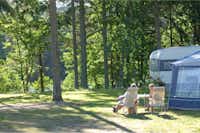 Vestbirk Camping- Camperpaar vor ihrem Wohnwagen in der Sonne