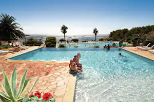 Village de Vacances Naturiste La Chiappa - Pool vom Campingplatz mit Liegestühlen in der Sonne und Blick auf das Meer