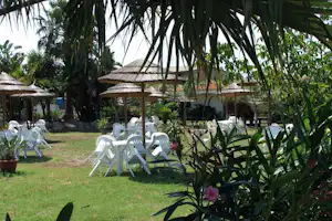 Villaggio Camping Calypso - Esstische unter Sonnenschirmen auf grüner Wiese vom Campingplatz