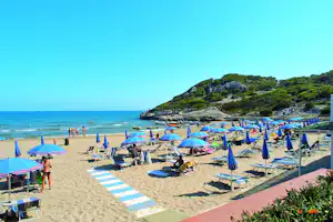 Villaggio Turistico Baia di Manaccora - Strand vom Campingplatz mit Sonnenschirmen und Liegestühlen am Mittelmeer