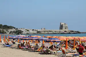 Villaggio Turistico Grotta dell'Acqua - Strand vom Campingplatz am Mittelmeer mit Sonnenschirmen und Liegestühlen