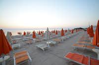 Villaggio Turistico Le Dune  -  Strand vom Campingplatz mit Sonnenschirmen und Liegestühlen bei Sonnenuntergang