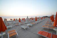 Villaggio Turistico Le Dune  -  Strand vom Campingplatz mit Sonnenschirmen und Liegestühlen bei Sonnenuntergang
