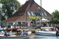 Vodatent @ Camping Eefting - Bootsanleger mit zahlreichen bunten Segelboten vor einem Restaurant mit gut besuchtem Außenbereich