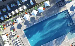 Blick auf den Campingpool mit blauem Wasser, Liegen und Sonnenschirmen sowie gepflasterten Wegen und Sitzbereichen.