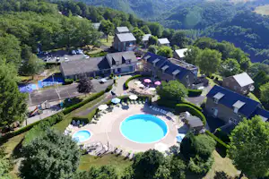 Luftaufnahme einer Campinganlage mit zwei Schwimmbecken, gepflegten Wegen, mehreren Gebäuden und viel Grün im Tal.