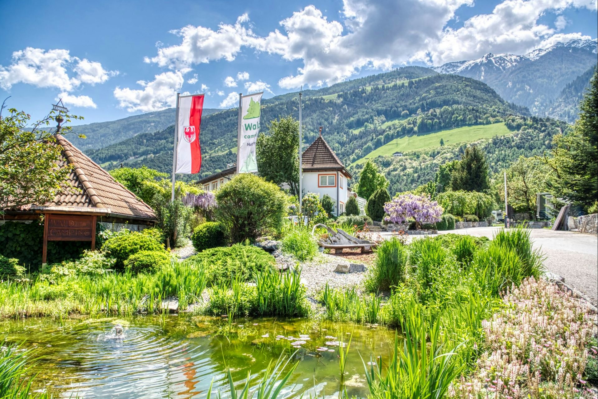 Waldcamping Naturns - Blick auf den Eingangsbereich mit Teich und Blumen