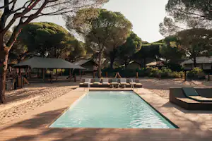 Schwimmbecken mit Liegen auf Holzterrasse, im Hintergrund Zelte und Bäume auf einem Campingplatzgelände.