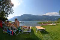 Wellness Seecamping Parth  - Liegestühle auf grüner Wiese am Ufer vom Ossiacher See am Campingplatz