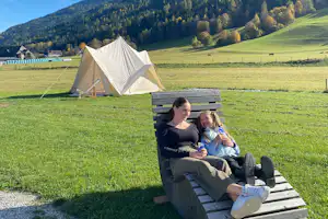 Wiesn Relax Camping Fam.Steiner Wiesn-Relax-Camping - Camperin mit Kind auf einem Liegestuhl auf der Wiese