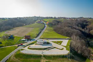 Luftaufnahme eines Campingplatzes im Tal mit Wohnwagen-Stellplätzen, Wegen und Gebäuden, umgeben von Wiesen und Hügeln.