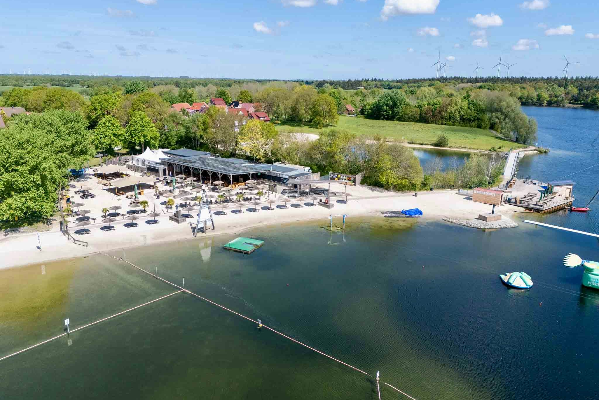 Wohnmobilpark am Badesee Aurich - Blick auf den Badestrand am See mit Strandbar