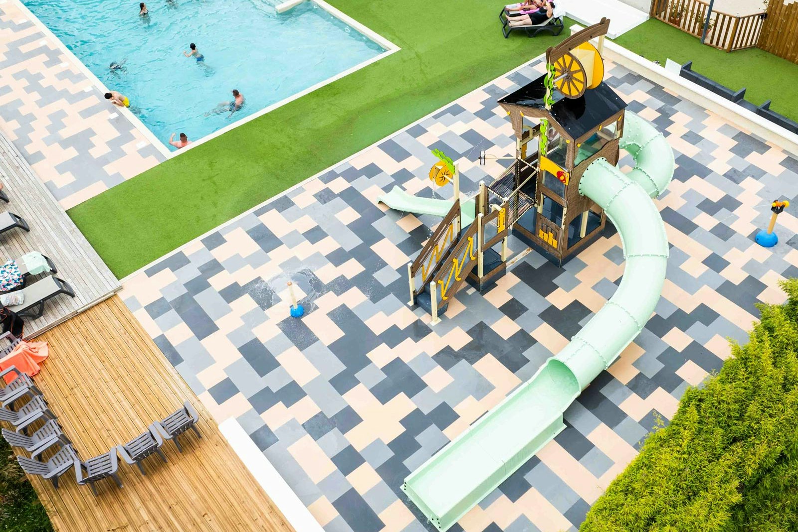 Kinder-Rutsche auf der Terrasse neben dem Pool, mit Liegen und Spielbereich auf dem Campingplatz.