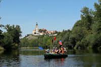 Zoopark Zelčín - Familie auf einem Schlauchboot auf dem Fluss mit Blick auf Ortschaft