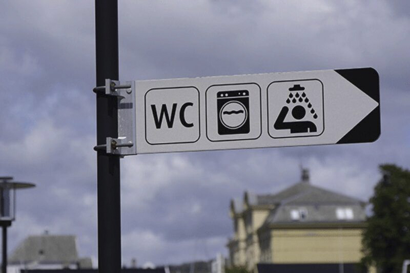Ein Schild, das den Weg zur Toilette zeigt.