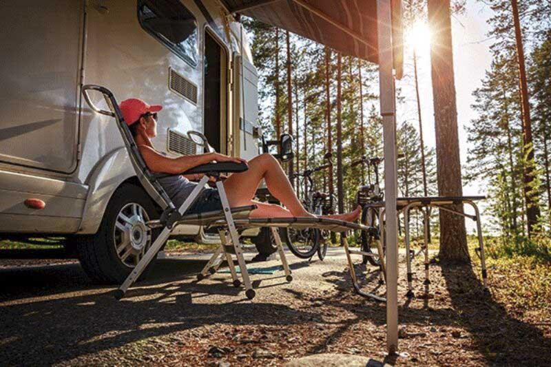Frau im Campingstuhl vorm Wohnmobil.