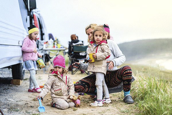 kinder-vor-einem-wohnmobil-in-jacken-am-strand