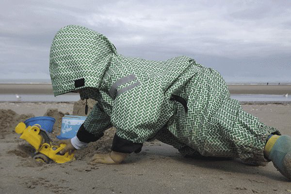 kleines-kind-spielt-am-strand-mit-einem-bagger.png