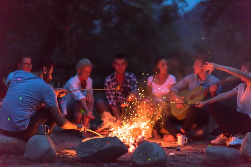 Jugendliche sitzen mit Gitarre am Lagerfeuer