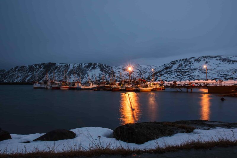 Bucht mit Booten während der Polarnacht nahe dem Nordkap bei Skarsvg, Norwegen