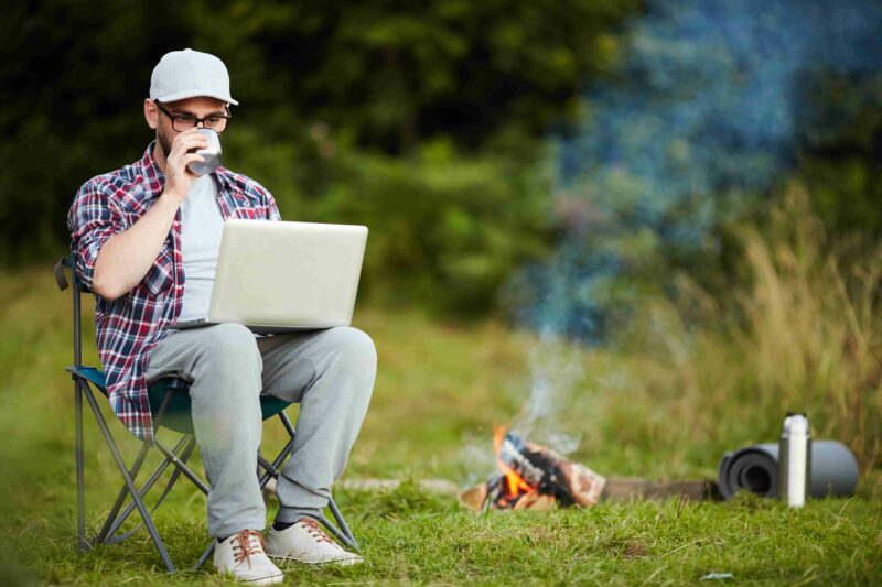 Camper-mit-dem-Laptop-im-Freien