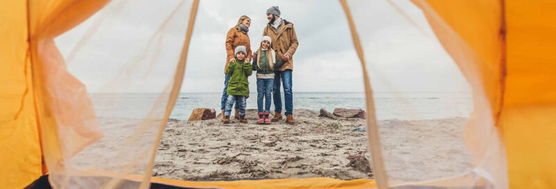 Familie beim Camping vor dem Zelt am Meer