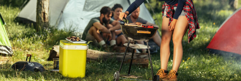 Camper beim Grillen auf dem Campingplatz mit Kühlbox