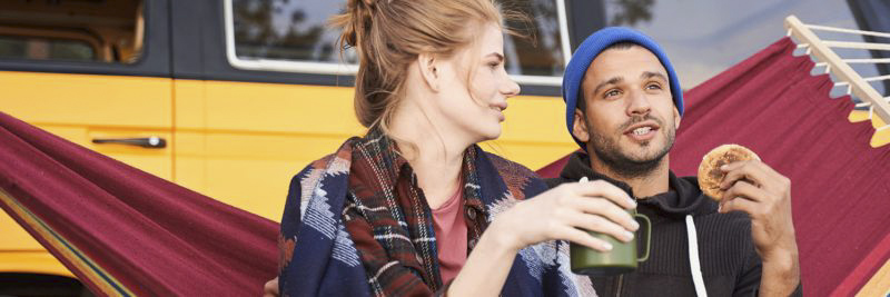 Pärchen sitzt vor Campingbus in Hängematte