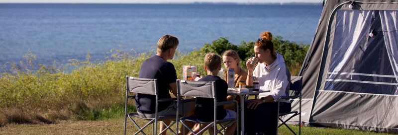 Eine Familie isst am Tisch beim Camping