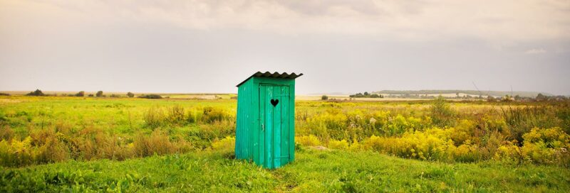 Hölzerne Toilette auf einer grünen Wiese