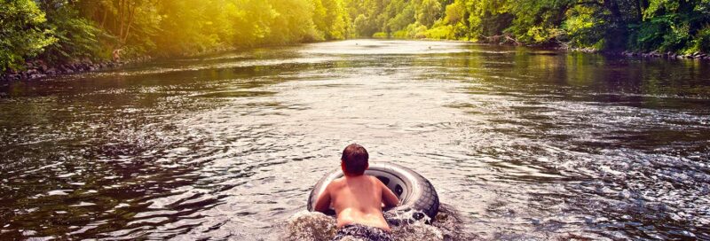 Kind schwimmt im Fluss mit Schwimmreifen