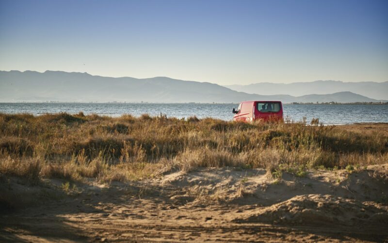 Strand im Ebro-Delta, wo Sie die typische Vegetation der Gegend, einen roten Wagen und das Mittelmeer sehen können