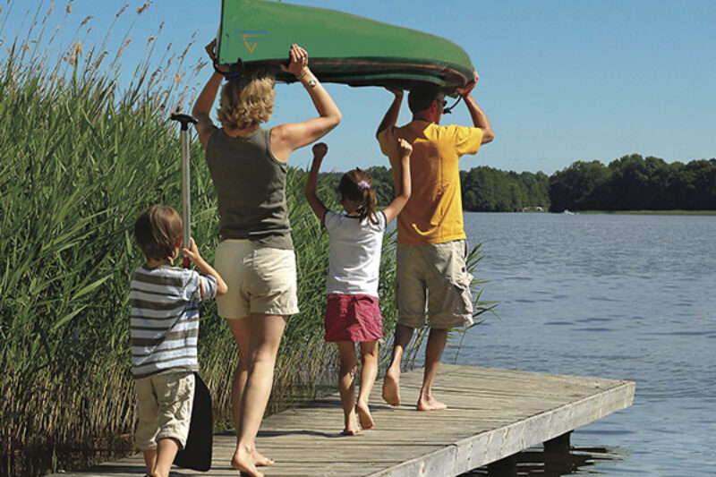 Familie trägt ein Kanu ins Wasser