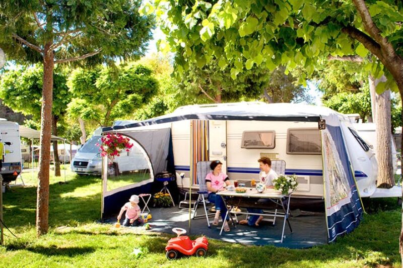 Camper sitzen vor dem Wohnmobil im Schatten der Markise